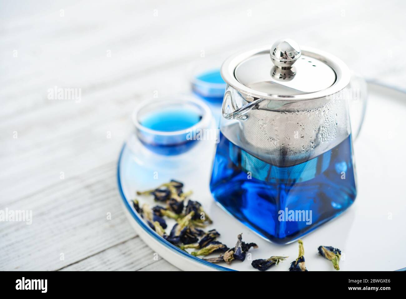 Due bicchieri di tè blu Anchan con teiera su sfondo bianco di legno Foto Stock