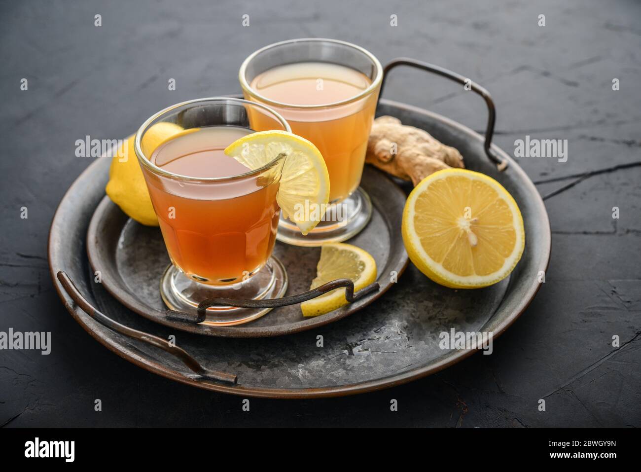 Tè Kombucha crudo fermentato in casa in vetro con limone e zenzero su sfondo nero Foto Stock