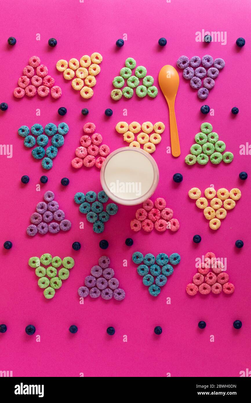 la rana si avvolse a forma di triangolo blu, verde, viola, rosa, arancione su un cartone rosa Foto Stock