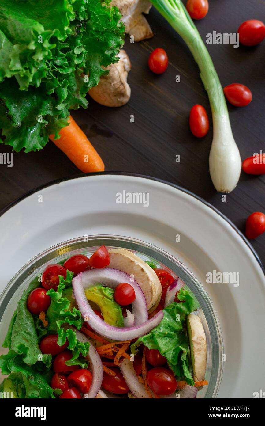 insalata di pomodoro di ciliegia, con funghi, cipolla su tavola nera, con alcuni motivi Foto Stock