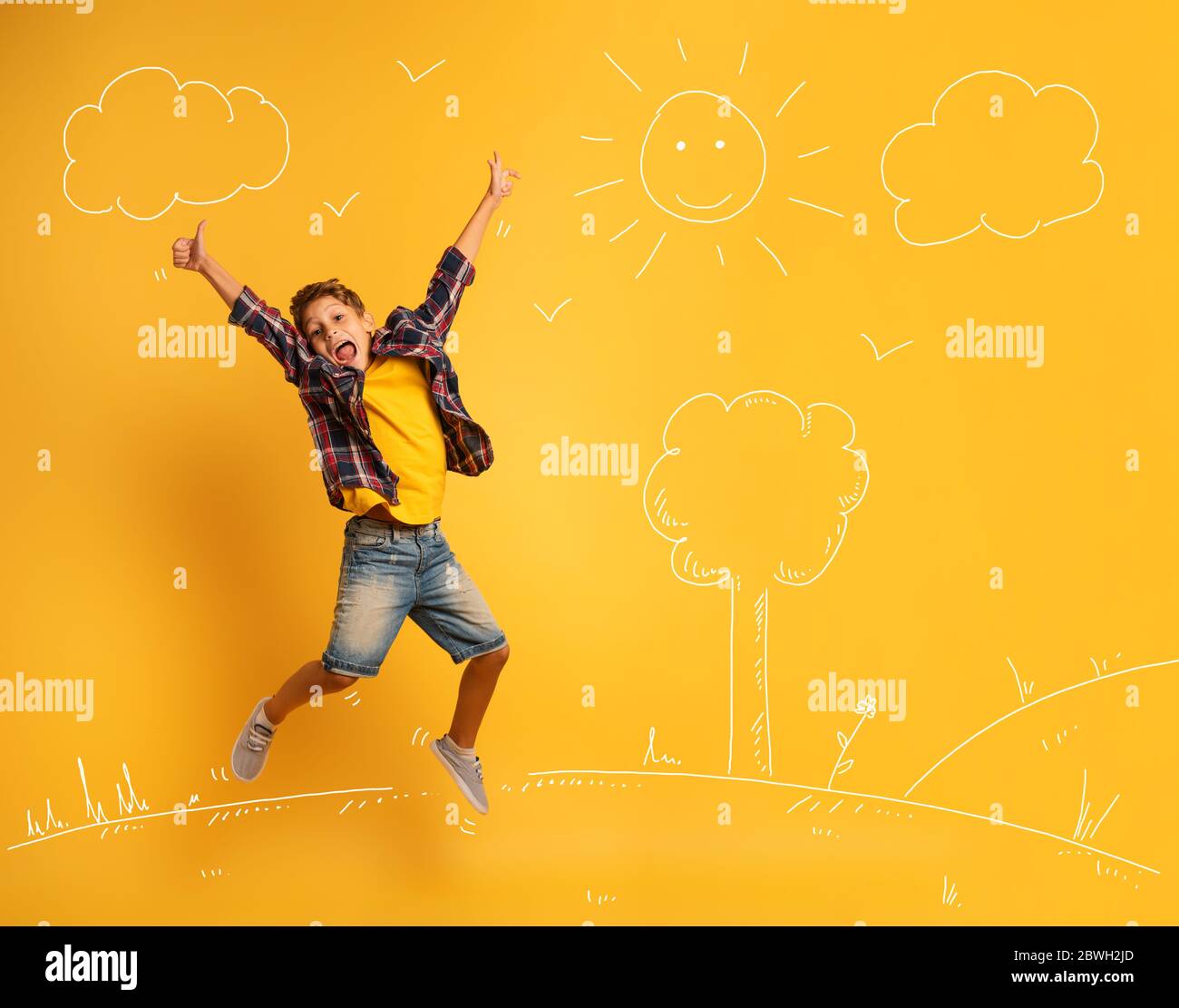 Bambino felice ed emozionale salta sopra uno sfondo giallo. Foto Stock