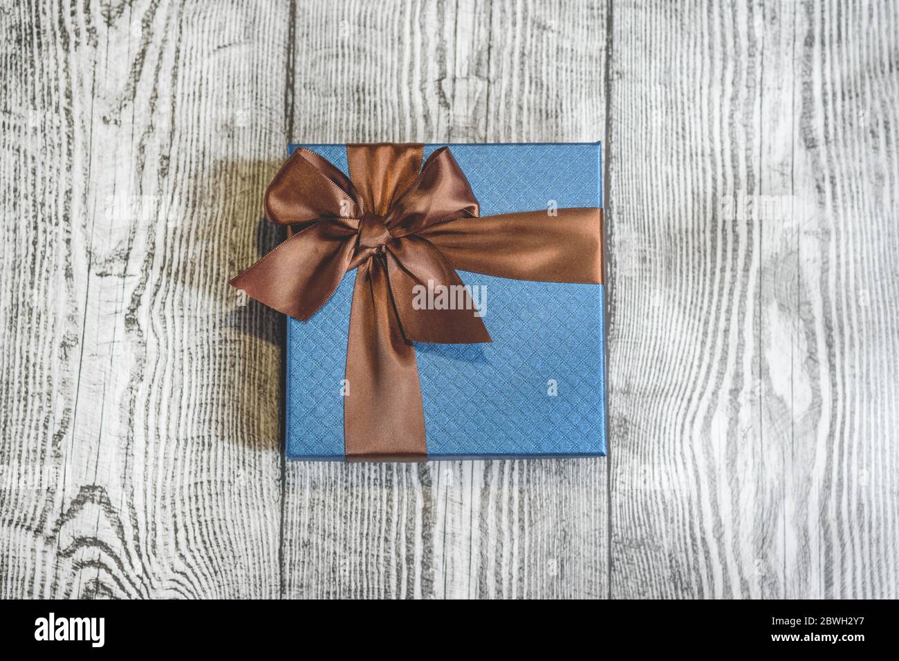 Un regalo blu con striscia marrone su sfondo di legno. Concetto di festa del Padre. Foto Stock