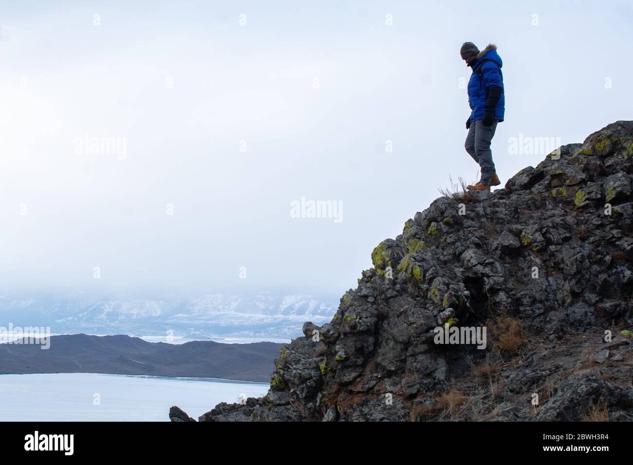 Uomo felice in piedi sulla scogliera e guardando la vista del paesaggio Foto Stock