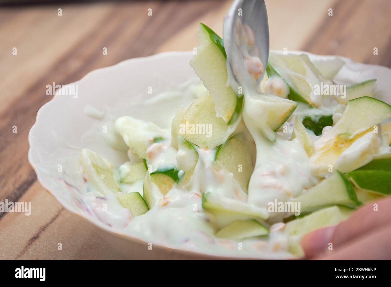 Mescolare le mele verdi con la banana e i cereali nello yogurt Foto Stock