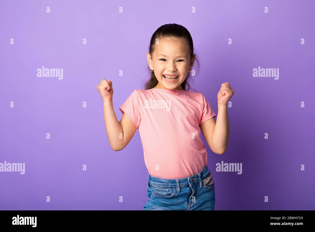 Felice ragazza asiatica agitando pugni, facendo gesto vincitore Foto Stock