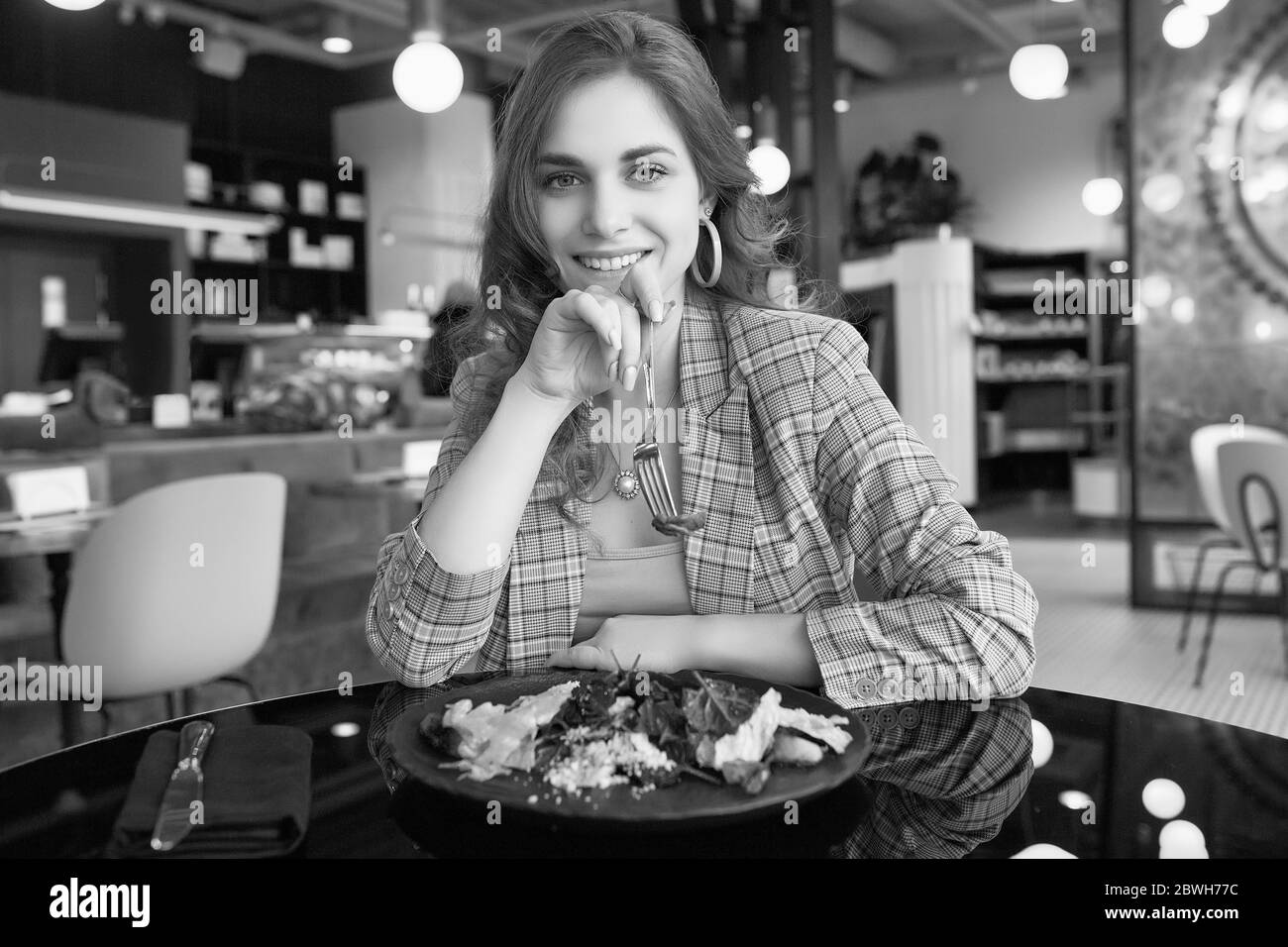 Ritratto di giovane bella donna sorridente che mangia cibo sano all'interno del bar Foto Stock