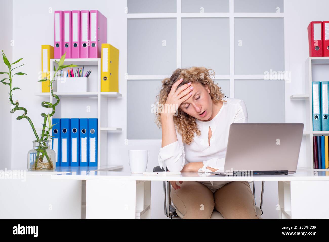 Donna d'affari overworked che soffre di mal di testa e pensare come terminare il lavoro. Stanco lavoratore d'ufficio. Donna ragazza che annoia in ufficio. Foto Stock