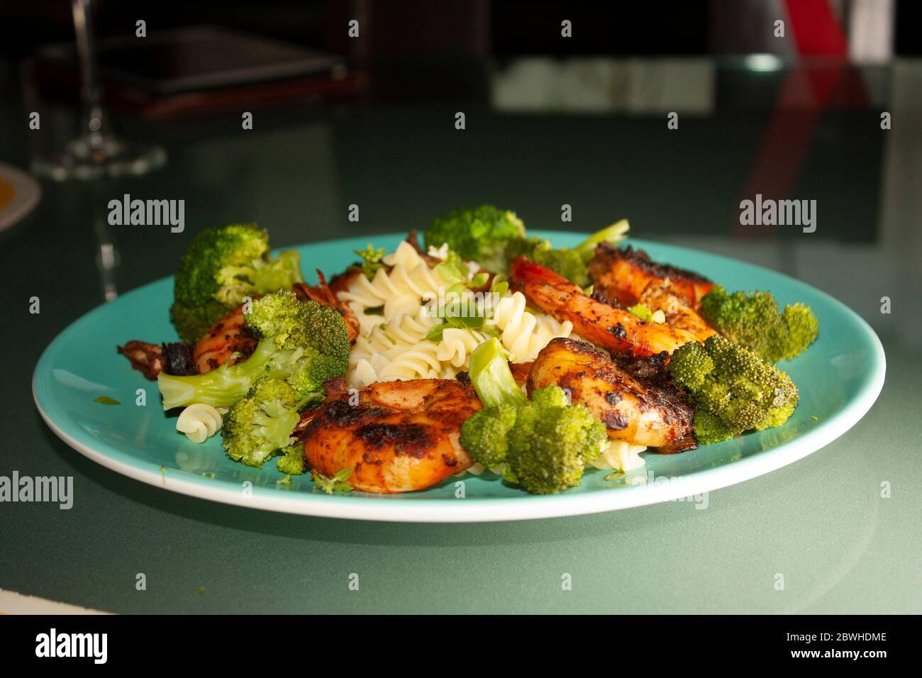 Gamberetti en la brizes enchilados con broccoli basilico has con fiori e pasta su piatto blu Foto Stock