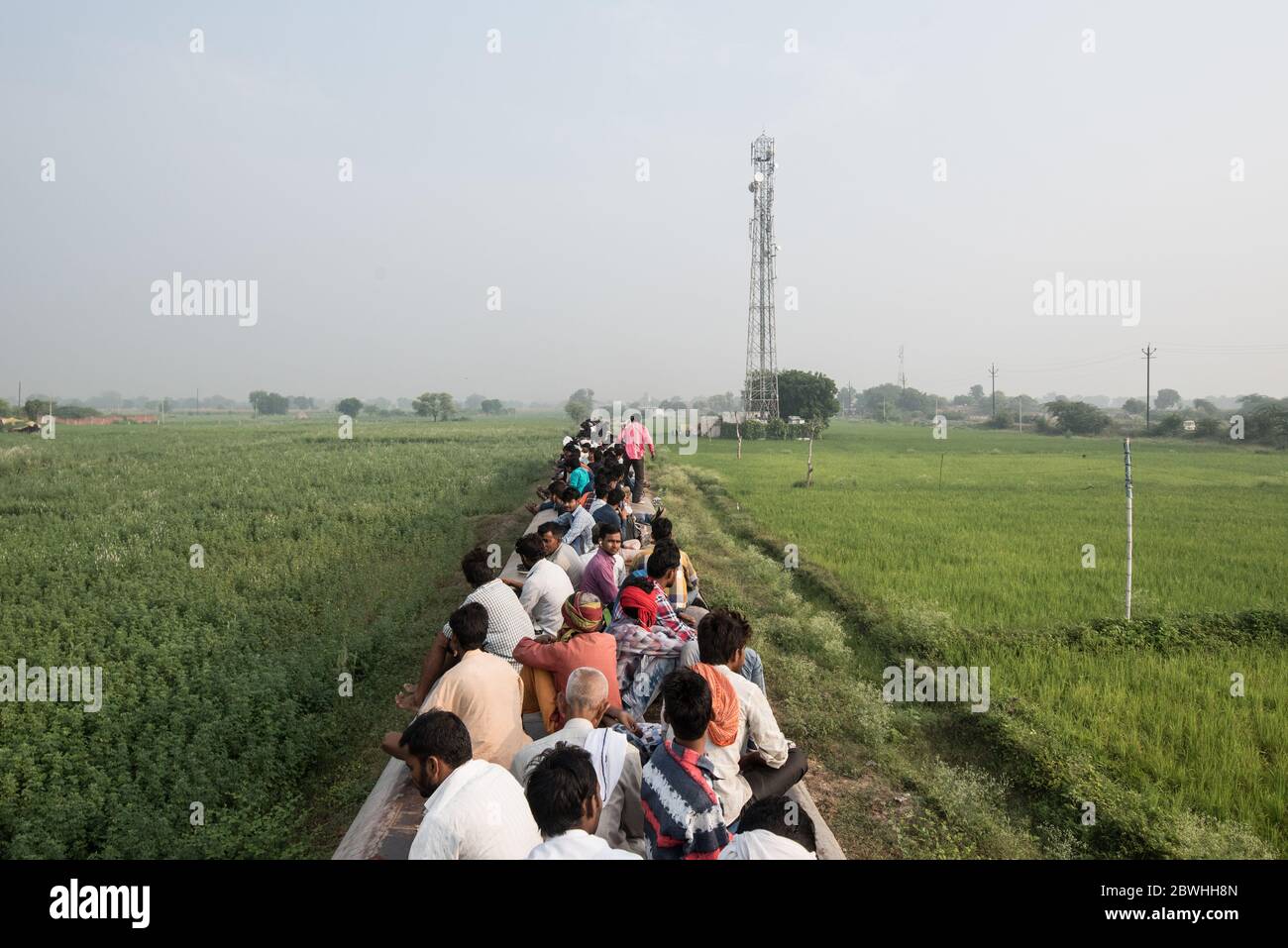 Uomini in cima a un treno sovraffollato che passa attraverso la campagna a Madhya Pradesh, India. Ferrovie indiane. Foto Stock