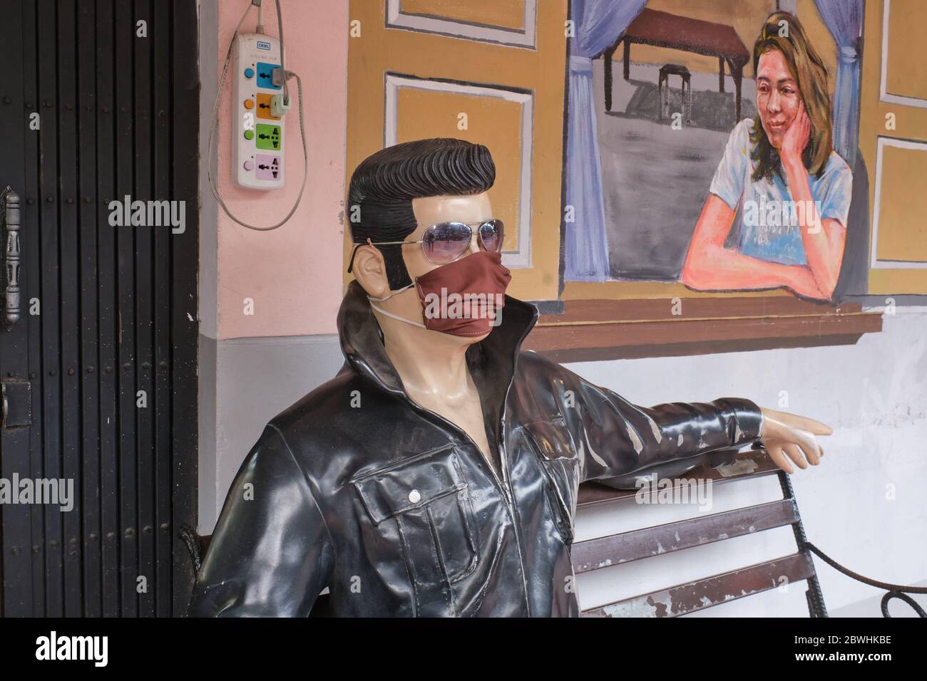 Durante la pandemia di Covid-19 (nCorona) nel 2020, una statua seduta di Elvis Presley di fronte ad un caffè a Bangkok, Thailandia, indossa una maschera facciale Foto Stock