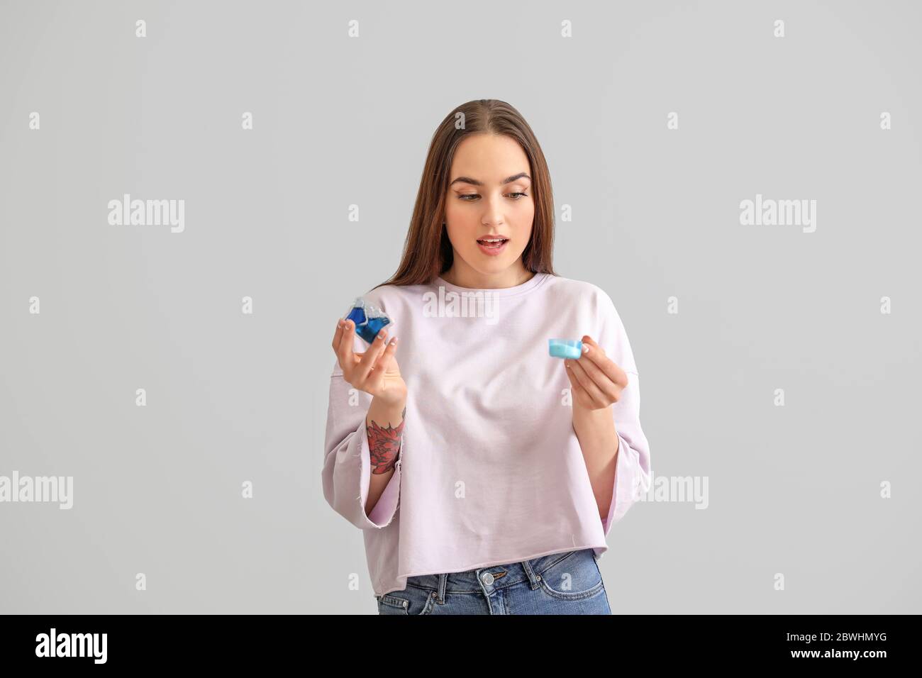 Giovane donna con detergenti su sfondo grigio Foto Stock