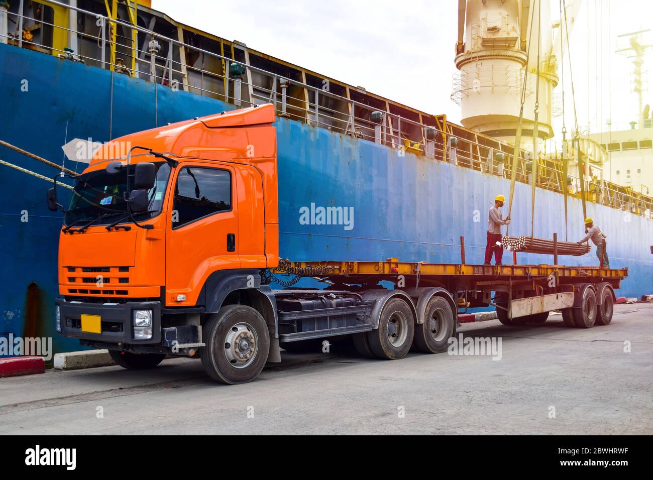 Operazioni portuali, carico di autocarri fascio di barre di acciaio lungo nave grande Foto Stock