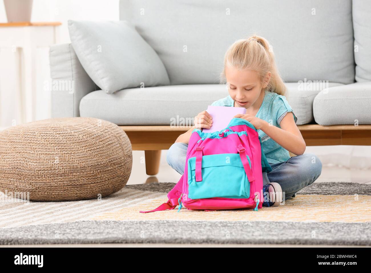 Carino bambina che imballano la borsa di scuola a casa Foto Stock