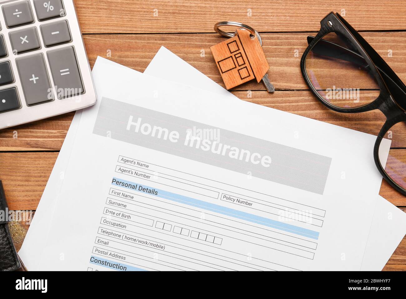Modulo assicurazione casa con chiave e calcolatrice su sfondo di legno Foto Stock
