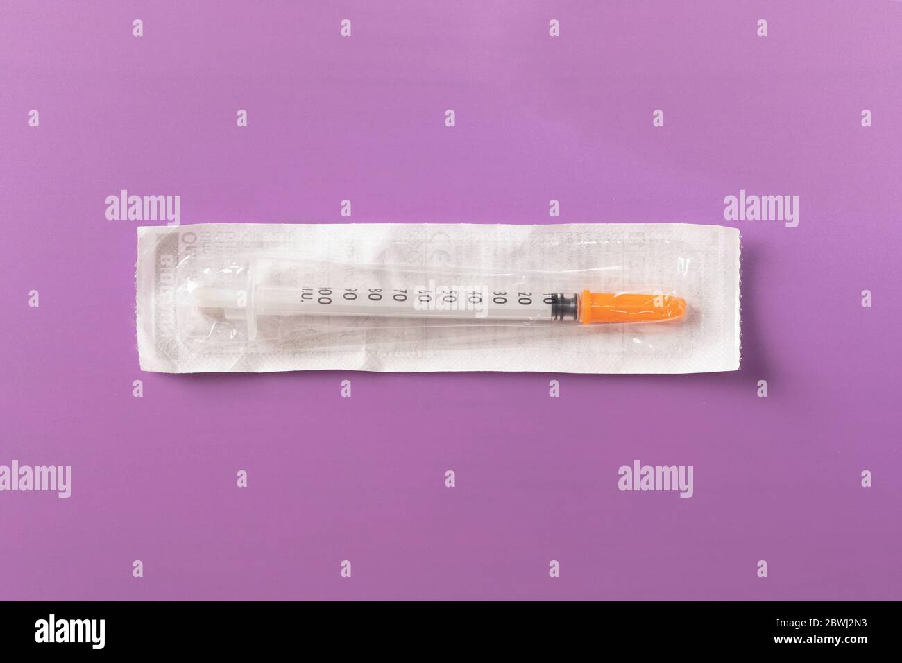 siringa monouso in plastica per insulina con ago nella confezione su sfondo  viola Foto stock - Alamy