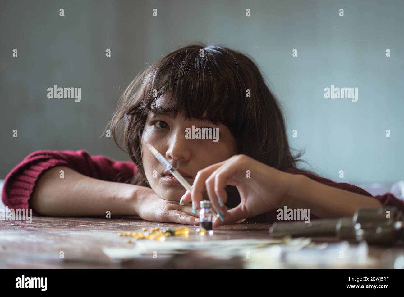 Concetto di droga. Donna tossicodipendente con siringa usando farmaci, ragazza asiatica con siringa usando farmaci. Foto Stock