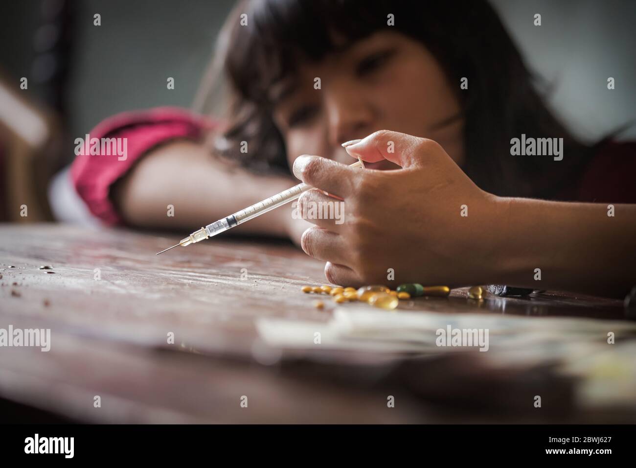 Concetto di droga. Donna tossicodipendente con siringa usando farmaci, ragazza asiatica con siringa usando farmaci. Foto Stock