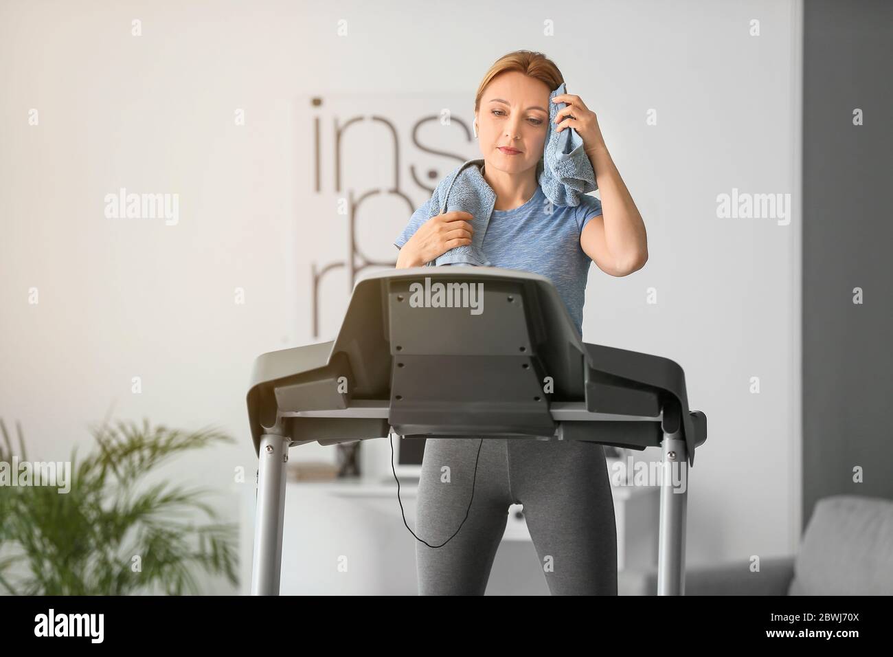 Donna sportiva che riposa dopo l'addestramento sul tapis roulant a casa Foto Stock