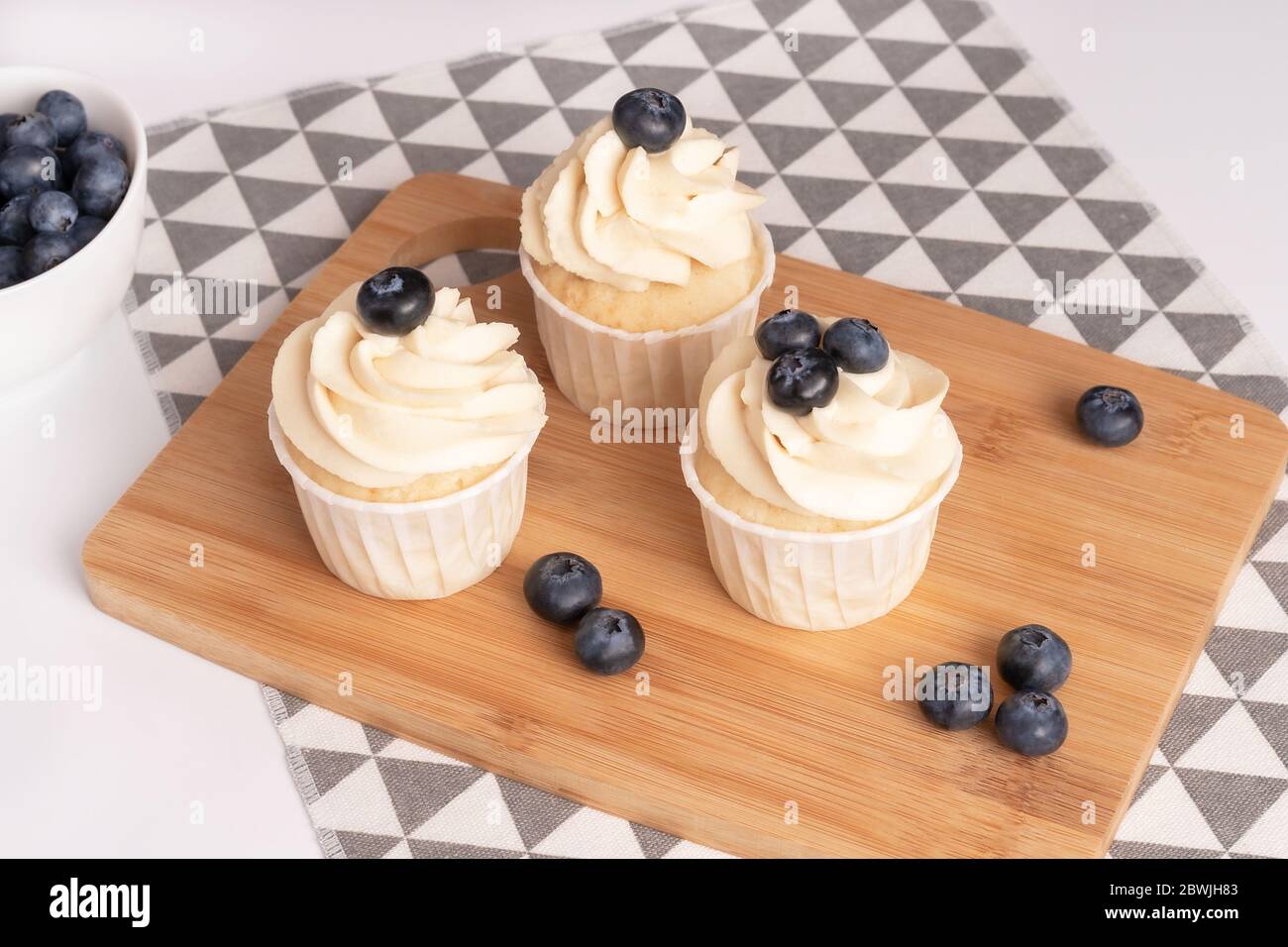 Cupcake fatti in casa con crema di mirtillo e vaniglia su tavola di legno. Primo piano. Foto Stock