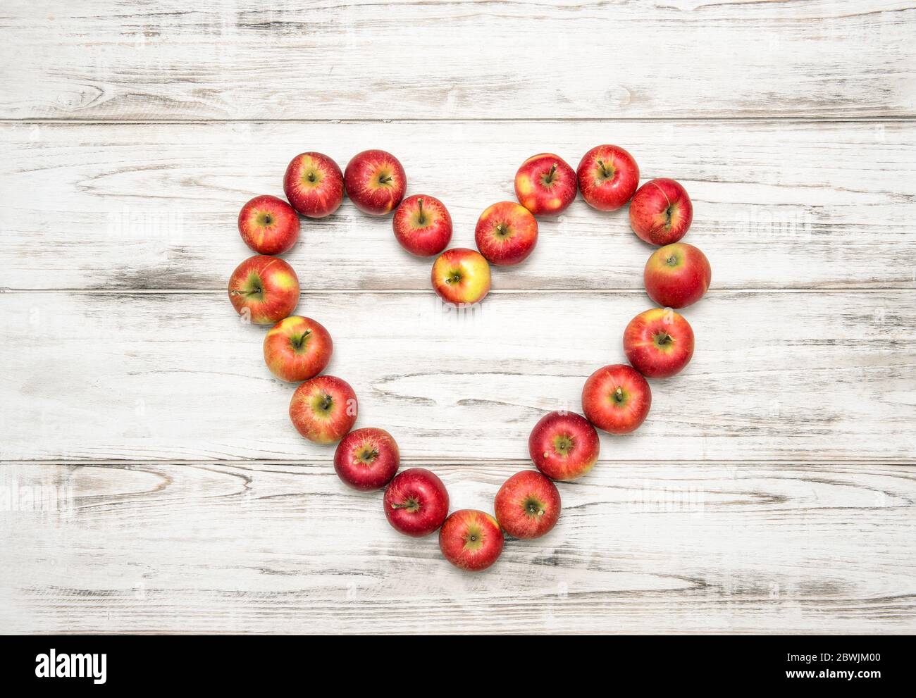 Cuore di mele rosse su rustico sfondo di legno. Concetto di amore Foto Stock