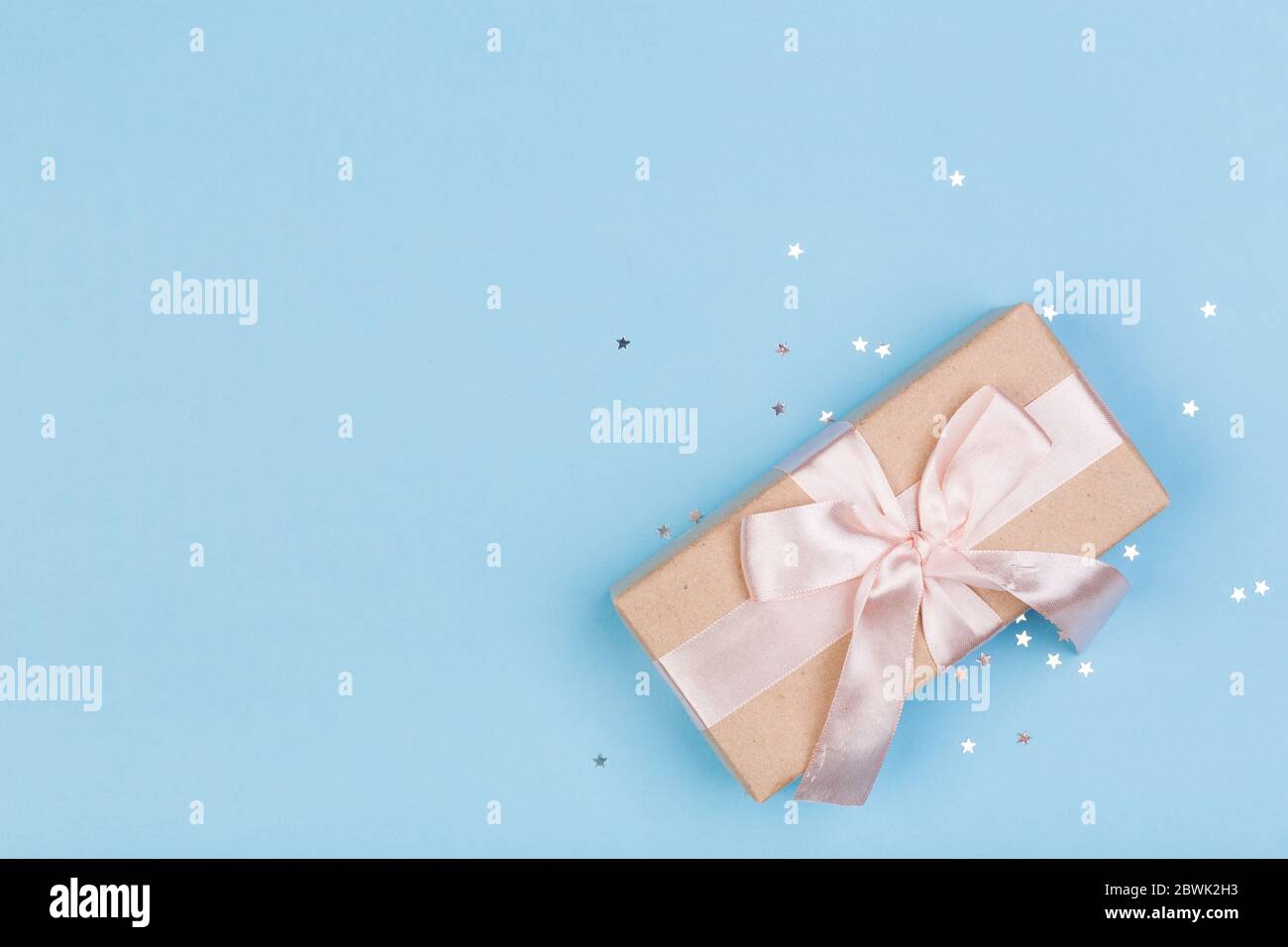 Confezione regalo o regalo e stelle confetti su un tavolo blu dall'alto. Composizione piatta per compleanno, giorno delle madri o matrimonio. Foto Stock