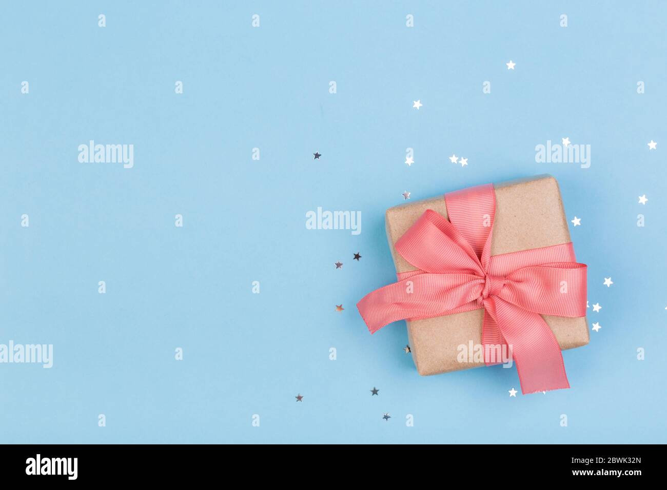 Confezione regalo o regalo e stelle confetti su un tavolo blu dall'alto. Composizione piatta per compleanno, giorno delle madri o matrimonio. Foto Stock