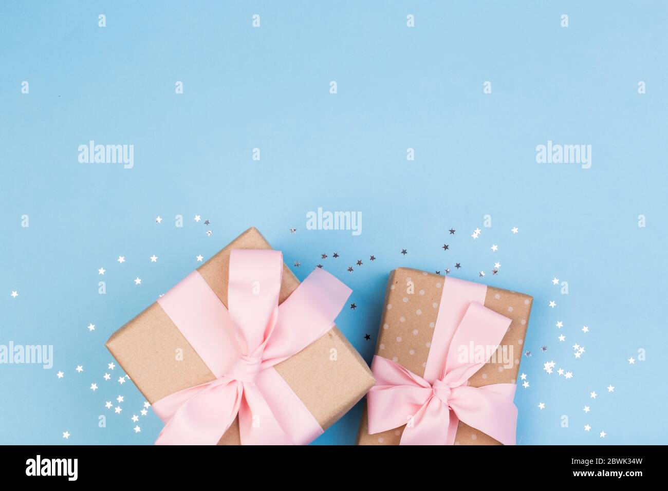 Confezione regalo o regalo e stelle confetti su un tavolo blu dall'alto. Composizione piatta per compleanno, giorno delle madri o matrimonio. Foto Stock