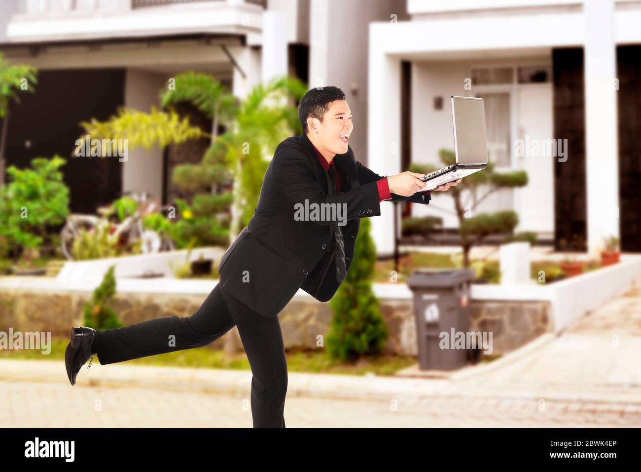 Uomo d'affari asiatico che corre mentre tiene un portatile. Concetto di detox digitale Foto Stock