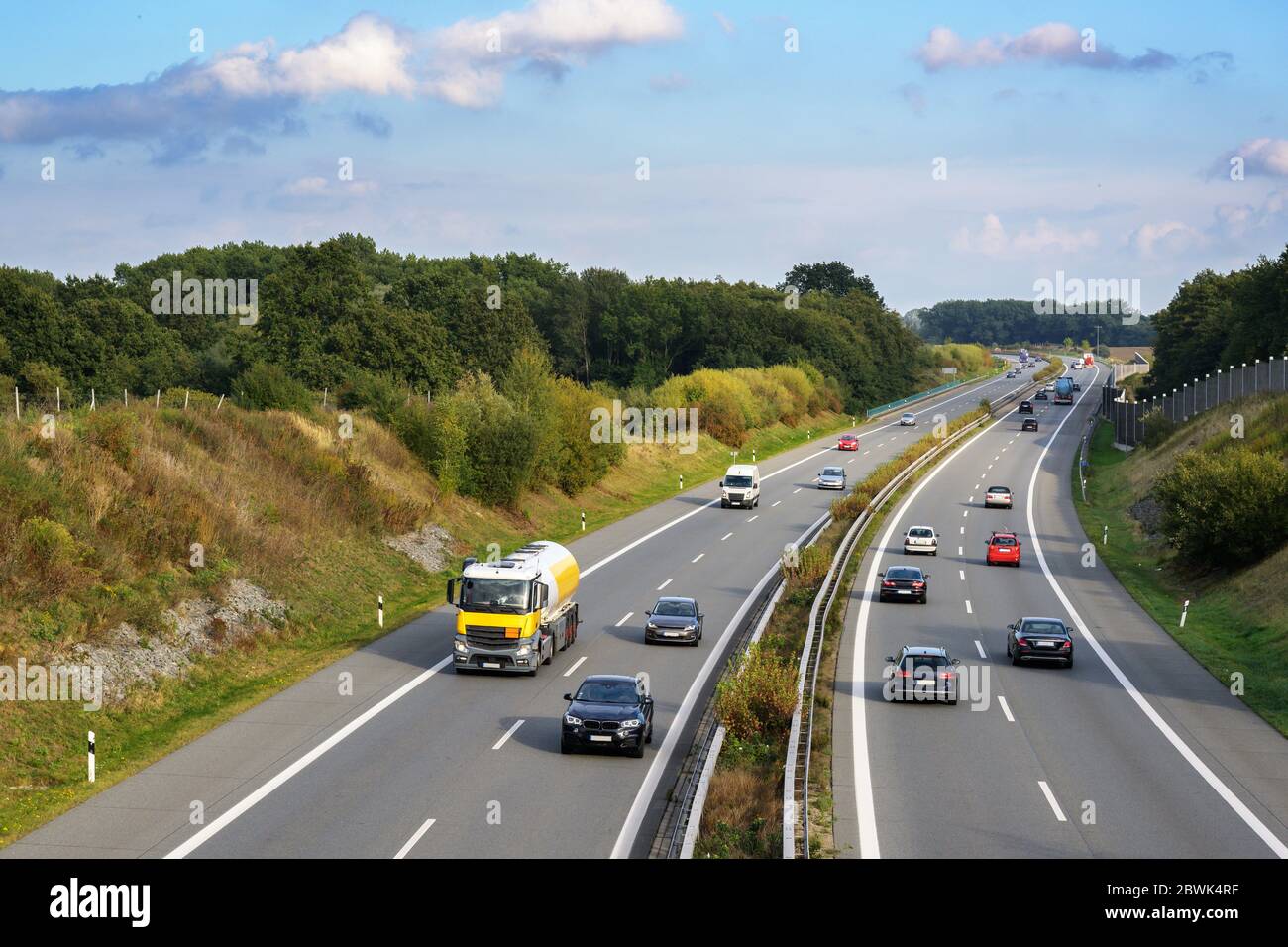 Auto e camion guidano in autostrada attraverso un paesaggio di paese, trasporti e ambiente concetto, cielo blu con nuvole e spazio di copia Foto Stock