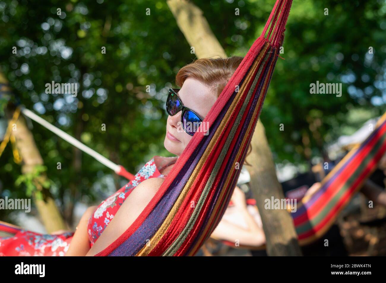 Ritratto esterno di giovane bella ragazza allegra bionda godere in amaca all'aperto. Rilassatevi nell'amaca nel giardino estivo Foto Stock