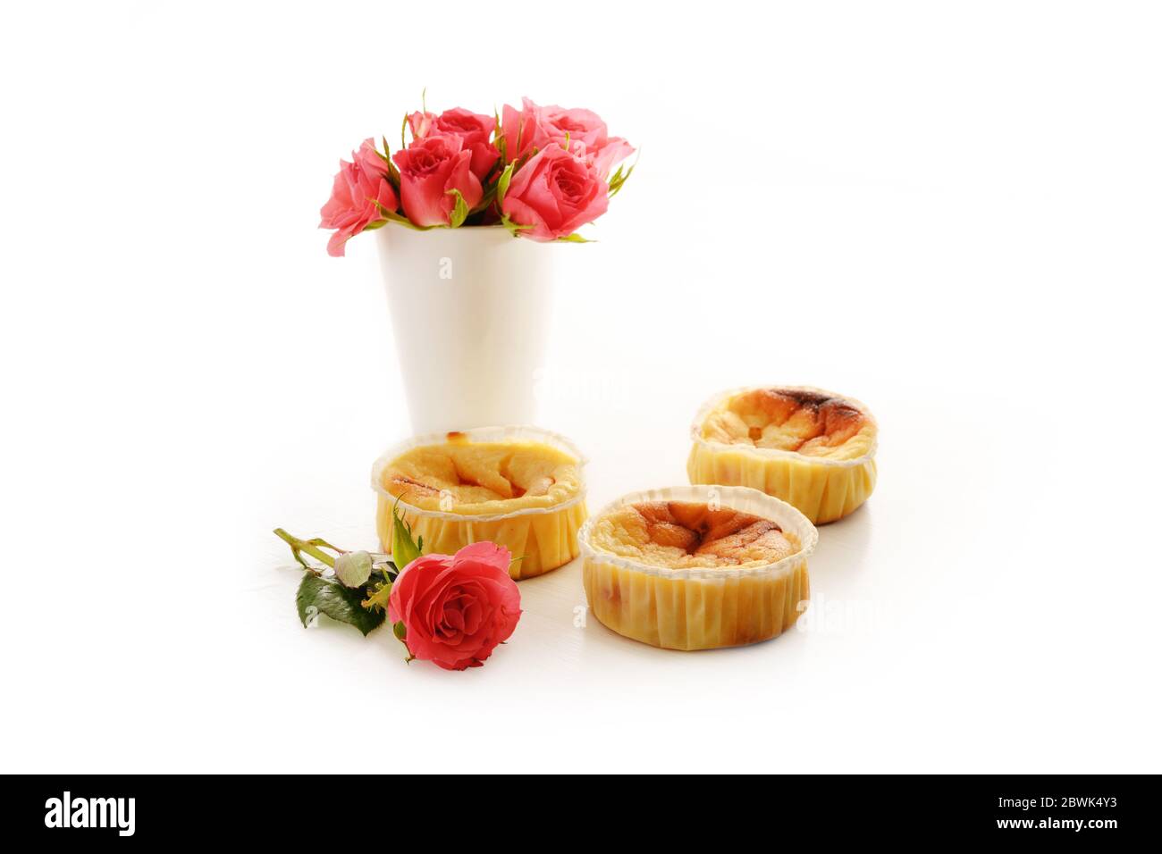 torte o muffin fatti in casa e un vaso con rose rosa isolato con ombre su sfondo bianco, spazio copia, fuoco selezionato, profondità ridotta Foto Stock