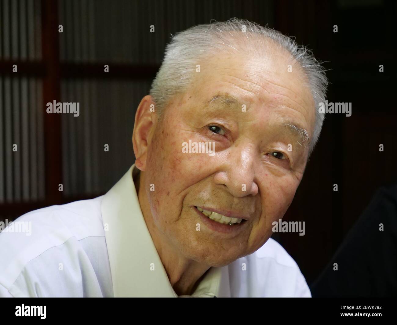 Un ritratto di un anziano asiatico che sorride nella fotocamera. Foto Stock
