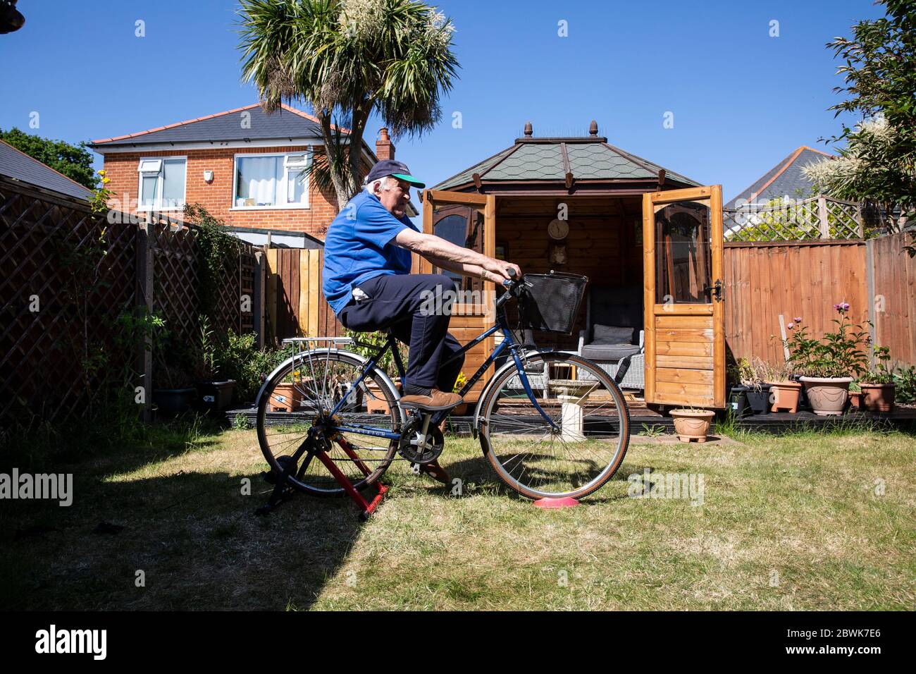 Coppie anziane sia nel loro 80 che tengono la misura su un supporto dell'addestratore della bicicletta nel loro giardino posteriore durante il lockdown del coronavirus, Inghilterra sudoccidentale, Regno Unito Foto Stock