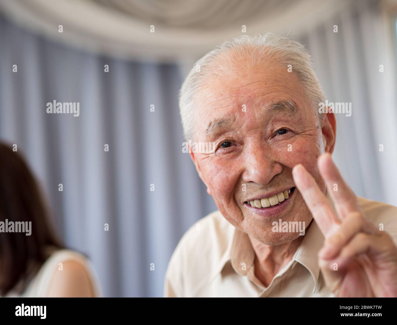 Un uomo anziano sorridente e mostrante un segno di pace Foto Stock