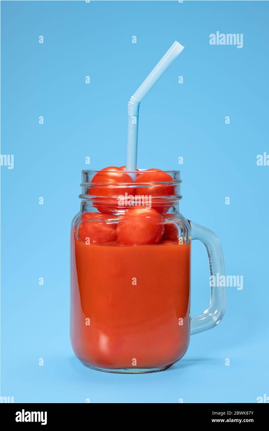 succo di pomodoro con pomodori freschi in tazza su fondo blu Foto Stock