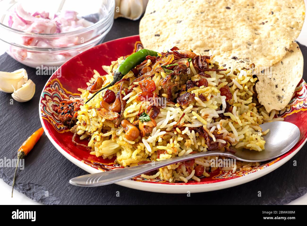 Pollo indiano halal o Biryani di montone servito con raita di pomodoro di yogurt su sfondo bianco. Messa a fuoco selettiva. Foto Stock