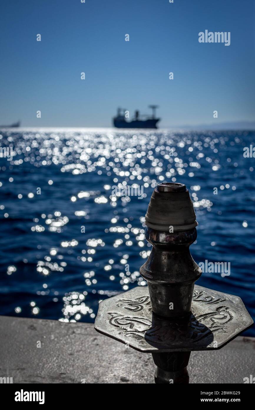 La cima di Hookah bella sceneggiatura sullo sfondo di blu offuscato acque del Mar Rosso in Giordania e sagoma di grande nave lontano. Incredibile calma inverno soleggiato giorno, contre-jour immagine Foto Stock