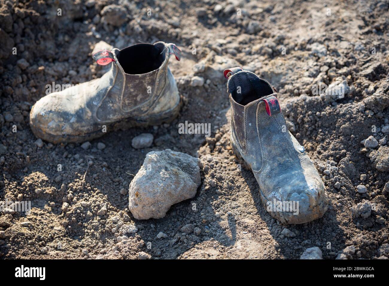 Profondità di campo bassa immagine di un costruttore stivali in acciaio capped nel fango Foto Stock