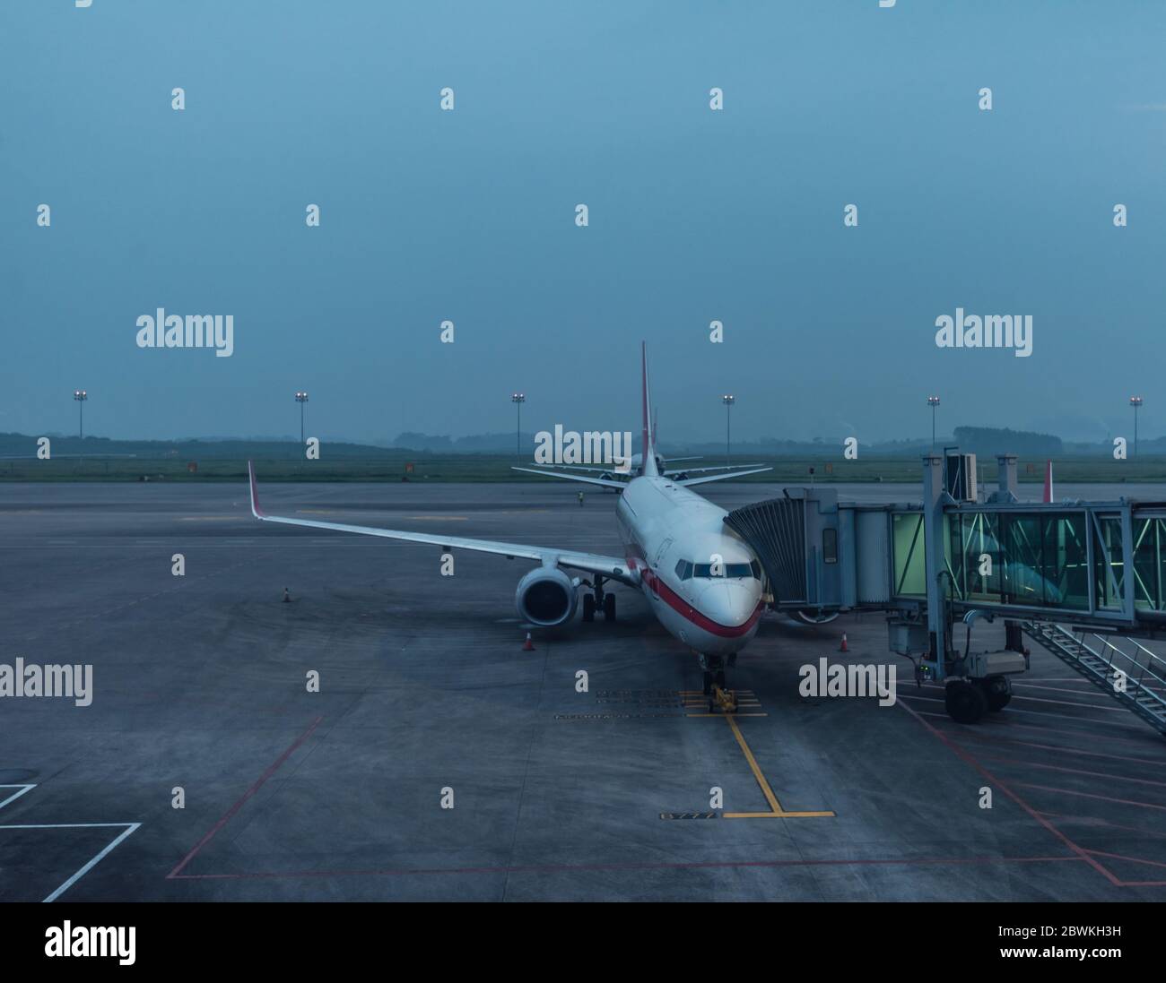 aereo al parcheggio vista dal finestrino della sala d'attesa del terminal aereo all'alba in una giornata nuvolosa Foto Stock