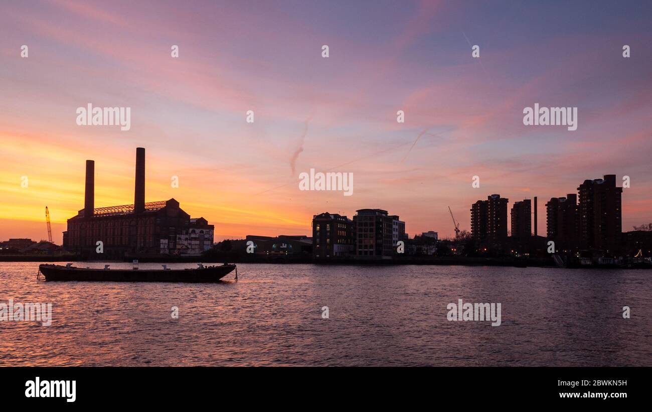 Londra, Inghilterra, Regno Unito - 27 febbraio 2013: Il sole tramonta dietro la stazione di alimentazione di Lots Road e gli edifici di appartamenti di conversione di magazzino sul Tamigi Foto Stock