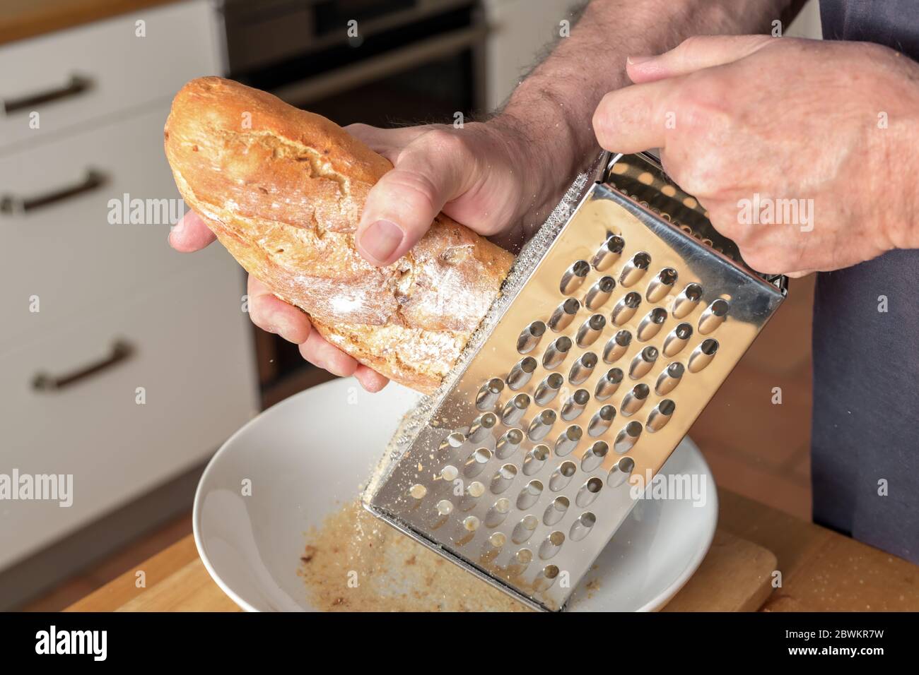 L'uomo sta grattugiando il pane duro su una grattugia per ottenere