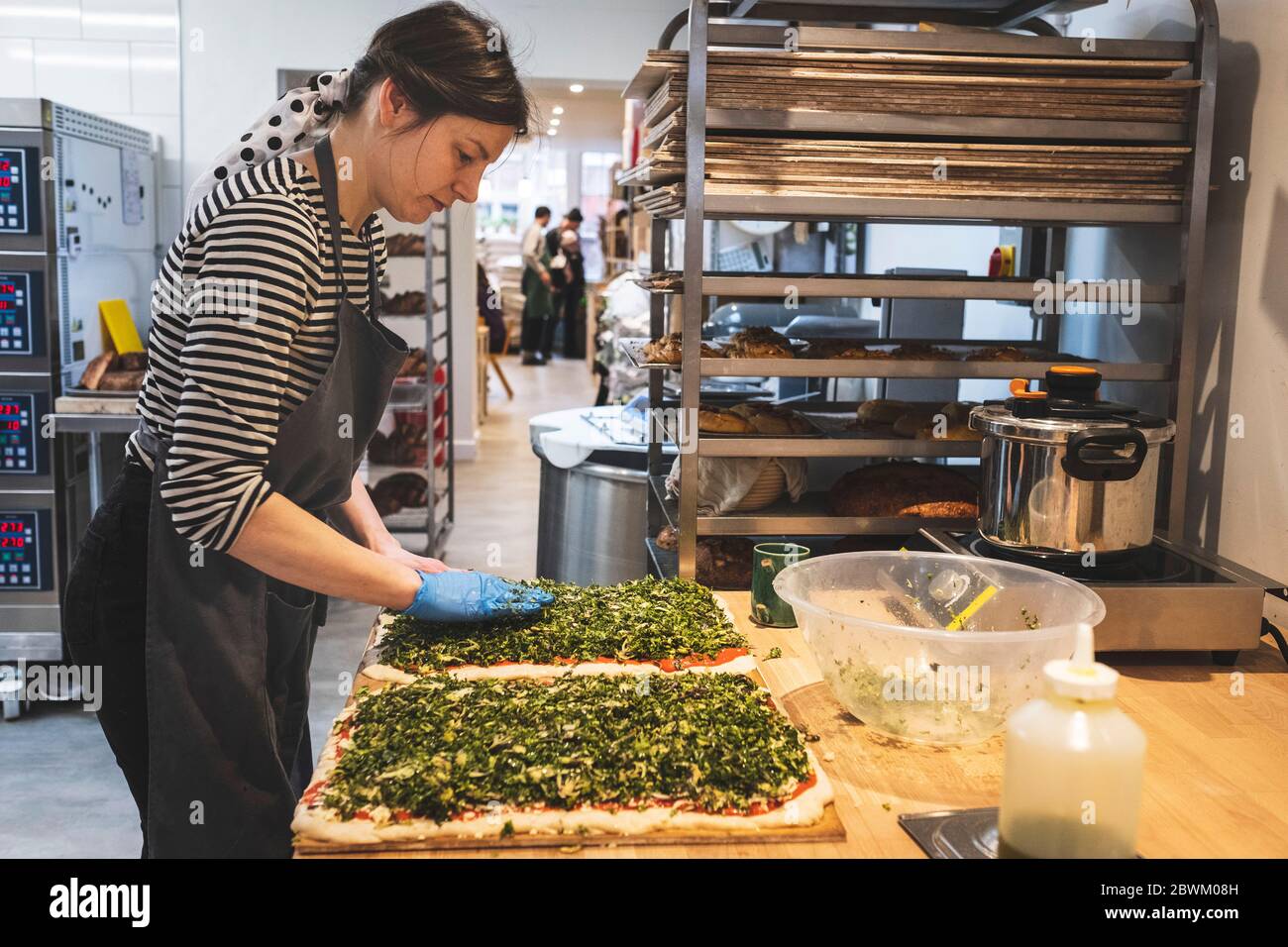 Un panettiere che fa una pagnotta saporita, spremendo le erbe e riempiendo l'impasto. Foto Stock