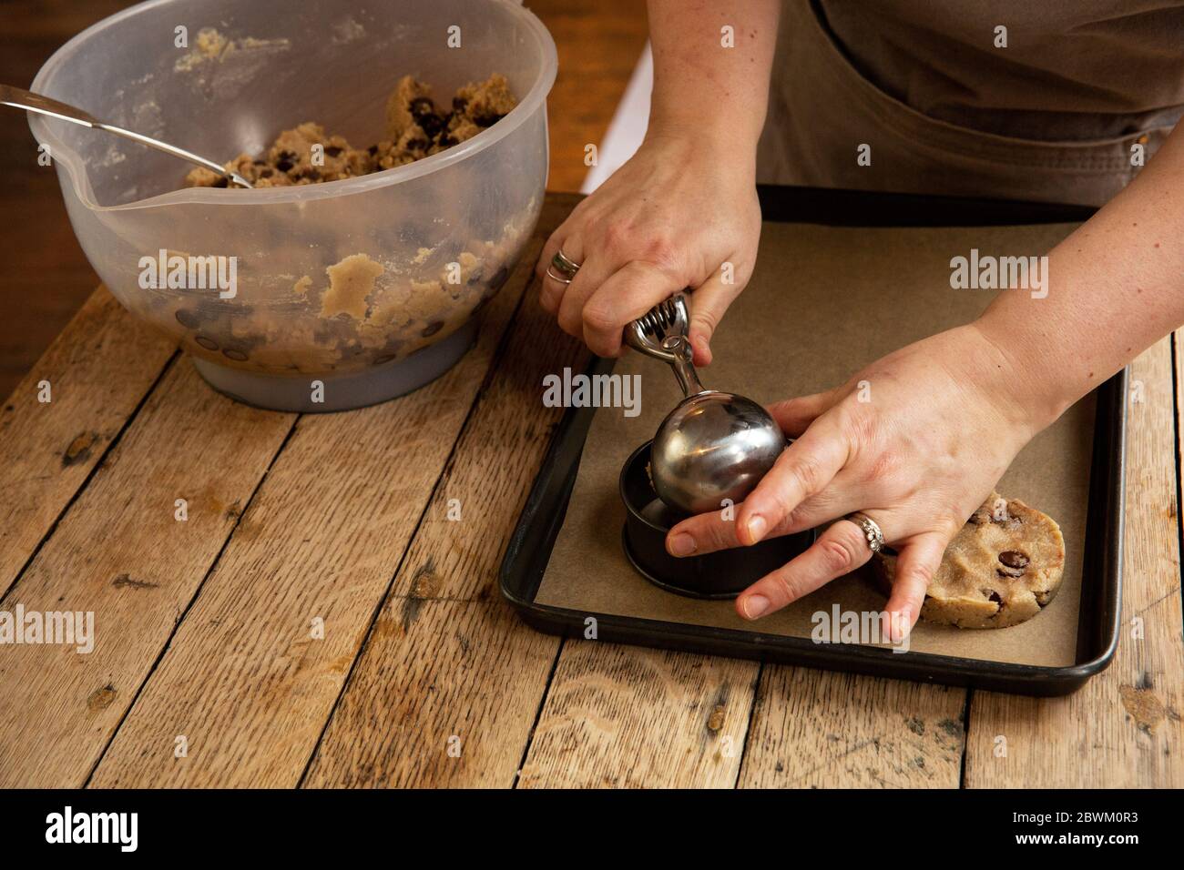 Angolo alto di persona in piedi a tavola di legno, cottura biscotti chip cioccolato. Foto Stock