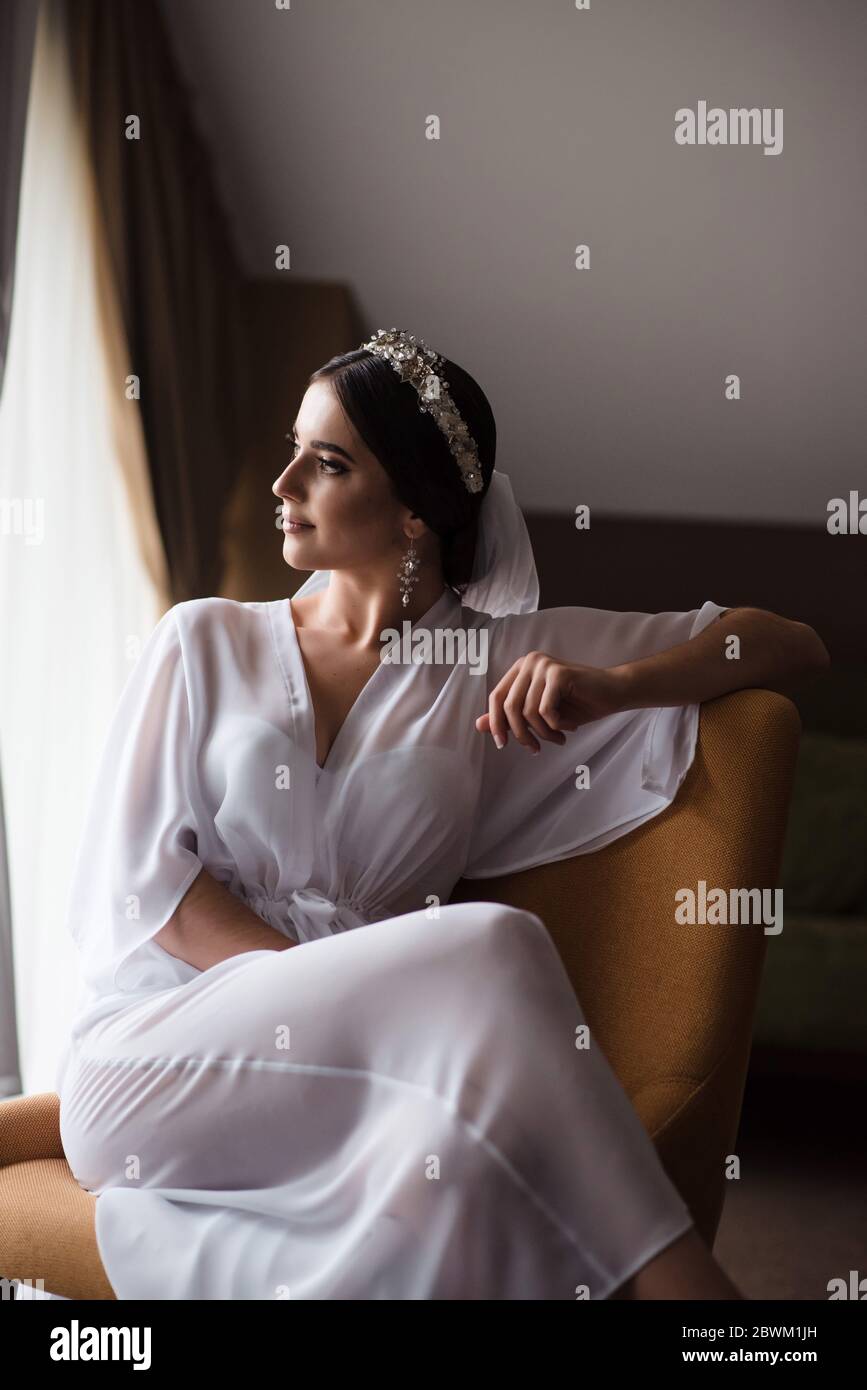 La mattina è stato fantastico sposarsi in camera. La sposa in un abito da  vestirsi si siede in una sedia nella stanza in attesa dello sposo Foto  stock - Alamy