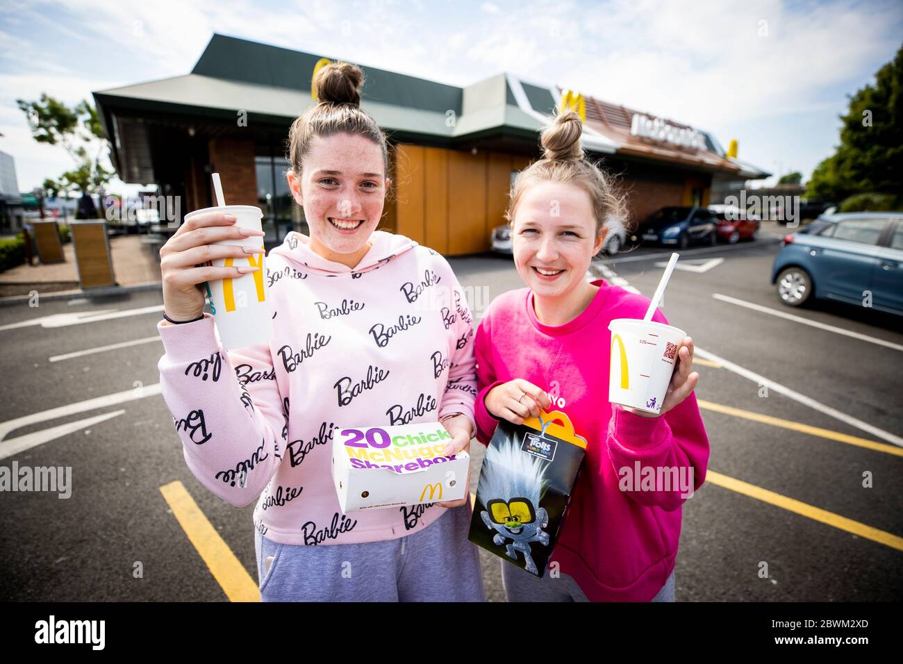 Zoe Mellon e Hannah Thompson di Bangor posano con il loro ordine di cibo al McDonald's riaperto drive-thru al Bloomfield Shopping Mall a Bangor, come le regole di blocco del coronavirus sono attenuate in Irlanda del Nord. Foto Stock