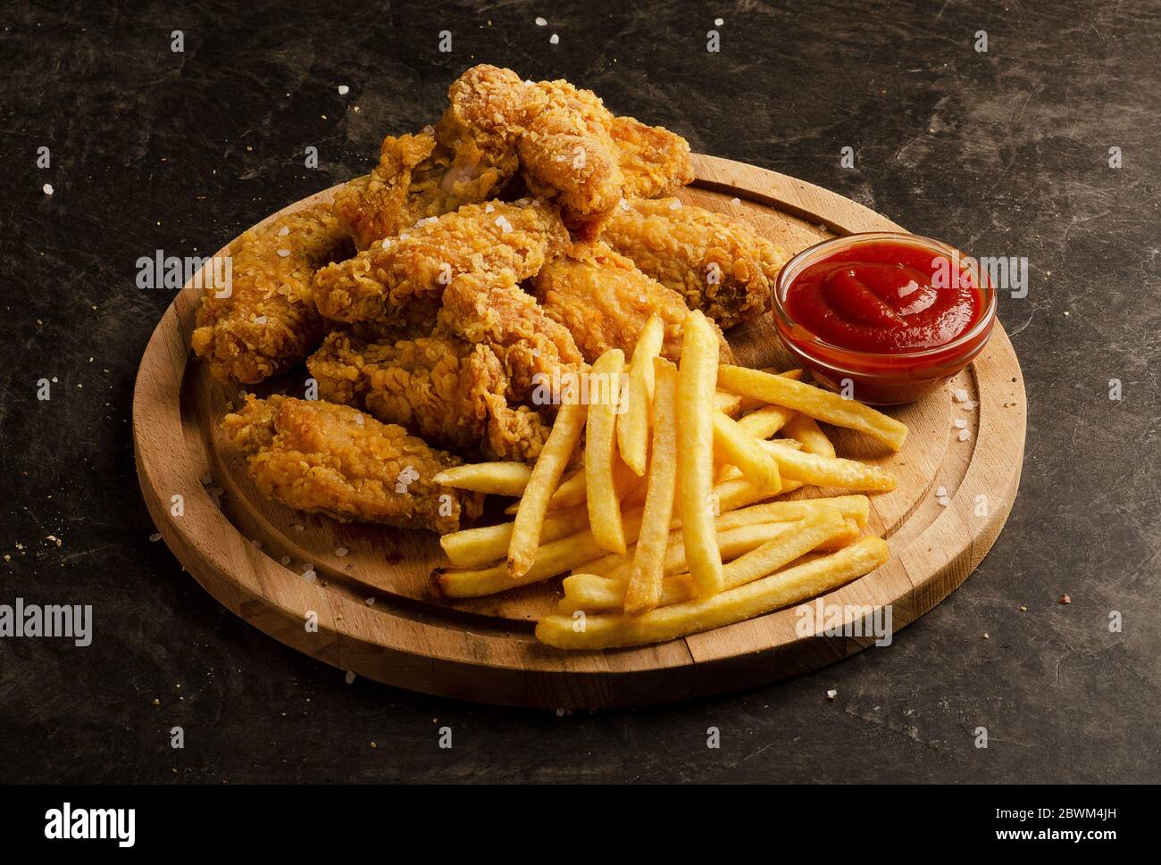 Ali di pollo fritte, patatine fritte e salsa di ketchup su sfondo scuro Foto Stock