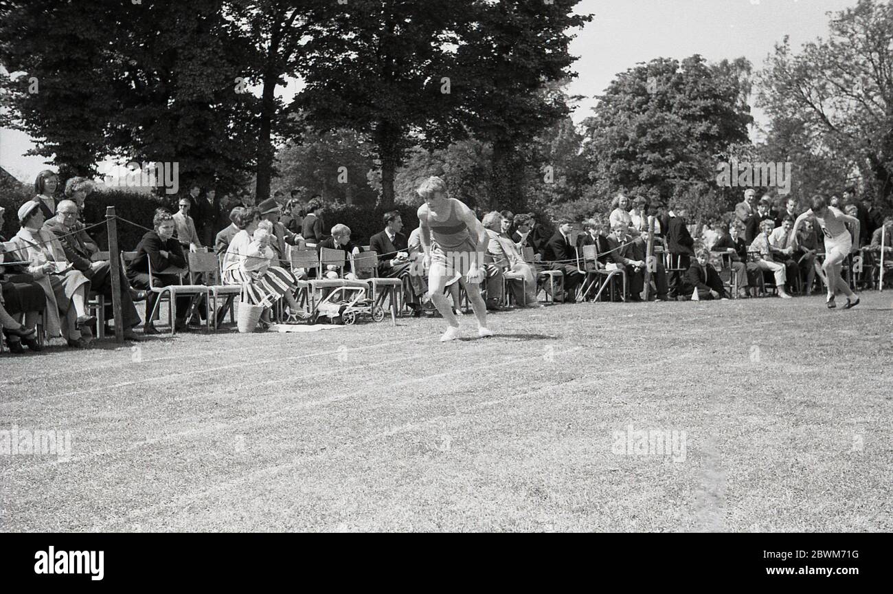 Anni '50, storico, estivo e sportivo scolastico, ragazzi adolescenti in attesa di inizio corsa, con mamme, papà, compagni di alunni e insegnanti seduti accanto alla pista di erba che sostiene gli atleti, Devon, Inghilterra, UK. Foto Stock