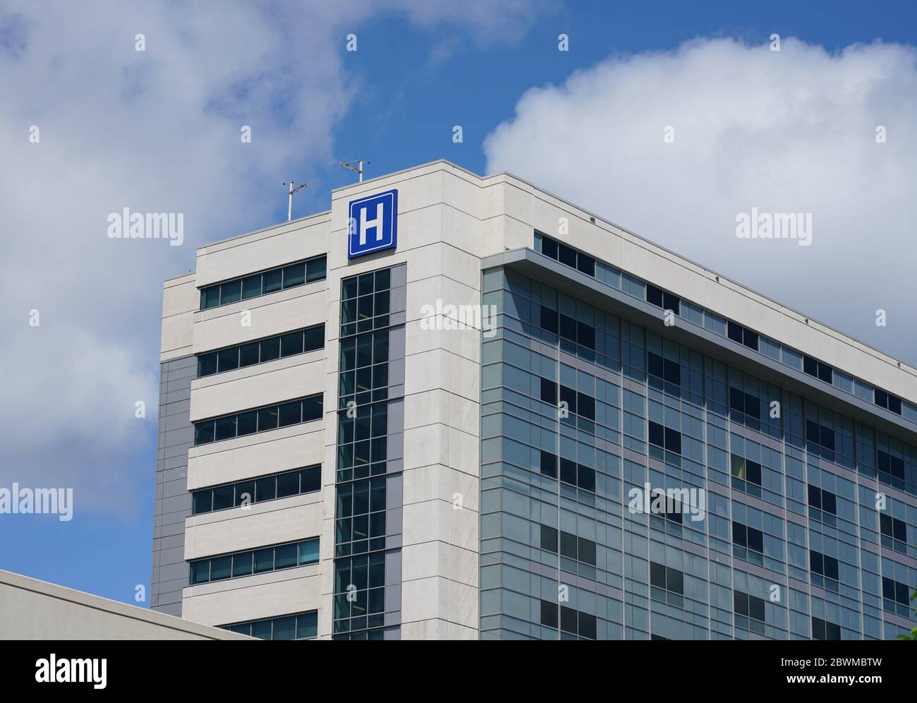 Grande edificio moderno con lettera blu, cartello H per l'ospedale Foto Stock