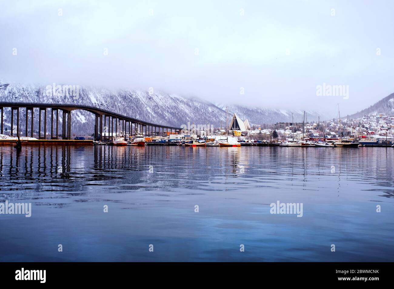 Tromso, Norvegia. Giornata nuvolosa nella famosa città settentrionale di Tromso, Norvegia. Vista sul fiordo con case, montagna e bellissimo ponte Foto Stock