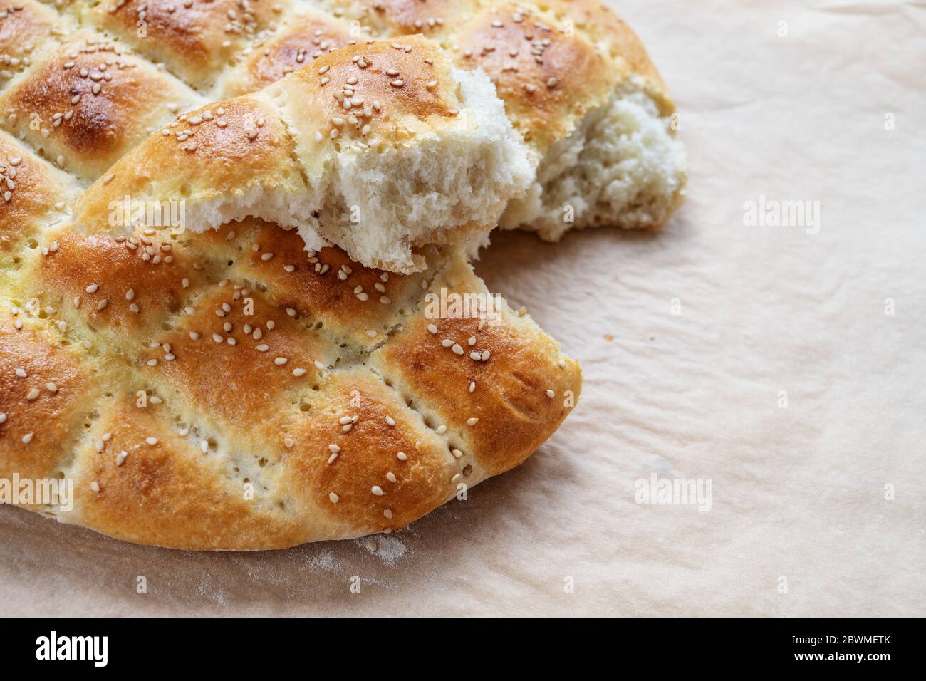 Pane piatto morbido appena sfornato nello stile della pide turca Ramadan su carta da forno, fuoco selezionato, profondità di campo stretta Foto Stock